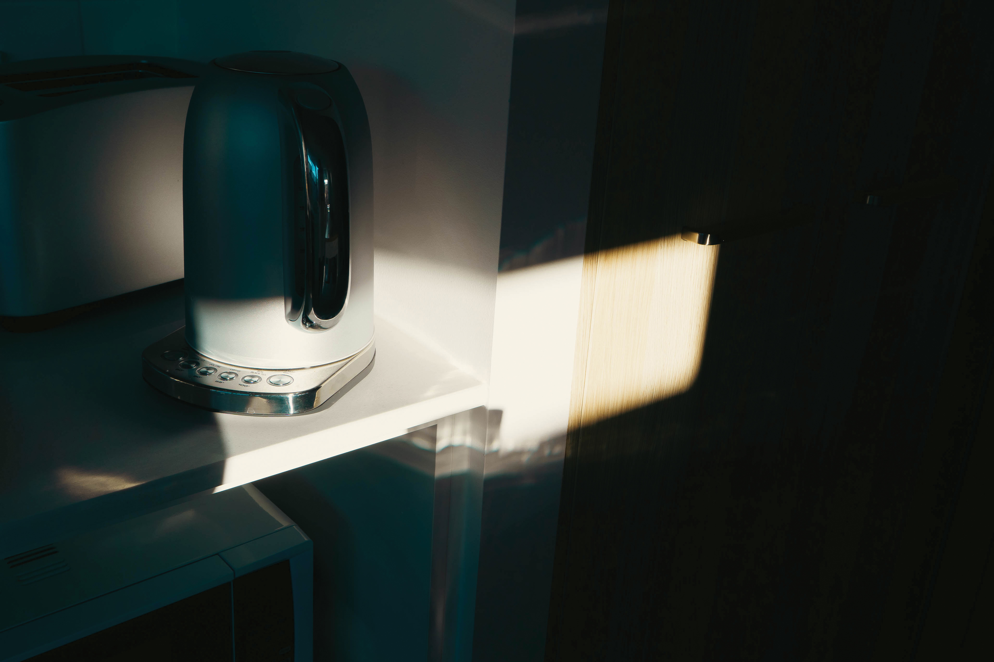 A kettle and harsh sunlight shadows in the kitchen