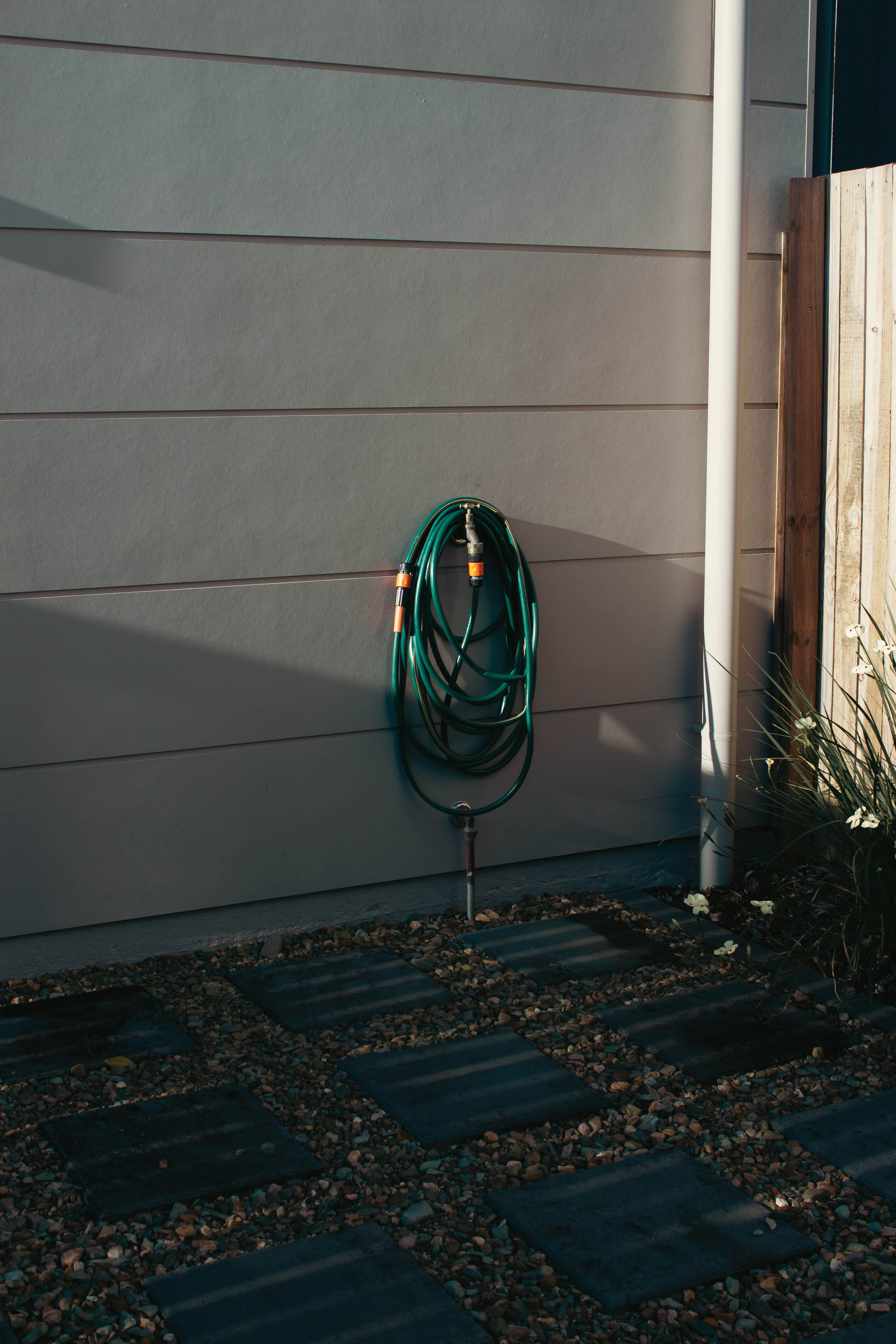 A faucet and hose attachment in a backyard at golden hour